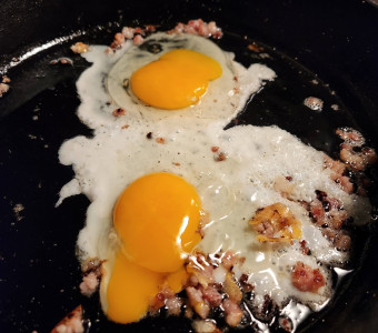 Eggs frying in a cast iron skillet.